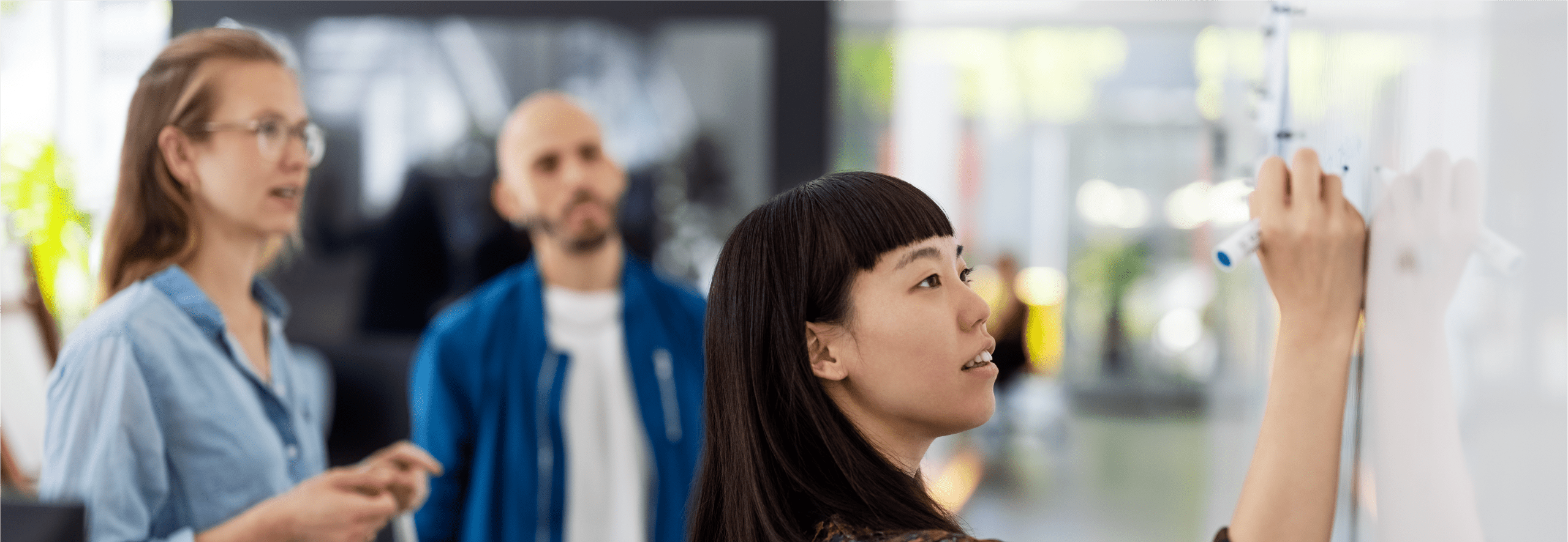 Business professionals brainstorming in a meeting and writing ideas on a whiteboard