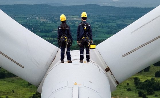 Two workers standing on top of a wind turbines representing representing the future of ESG