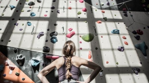 picture of a woman studying a climbing wall strategy