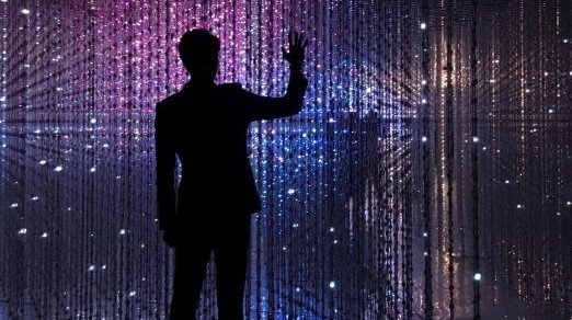 silhouette of man in front of digital wall of lights