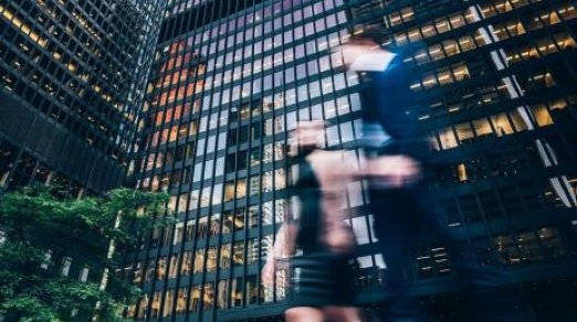 image of blurred people walking in front of corporate high rise building downtown