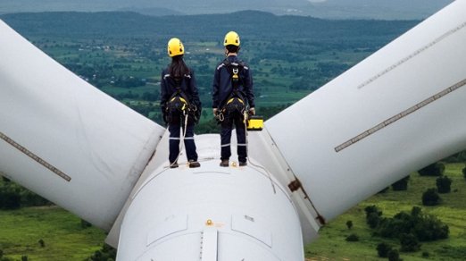 Two workers standing on top of a wind turbines representing representing the future of ESG